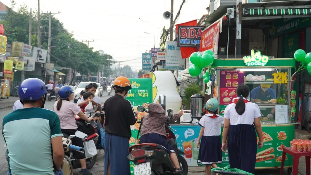 Kinh doanh bánh mì gần trường học với quầy bán và người qua lại