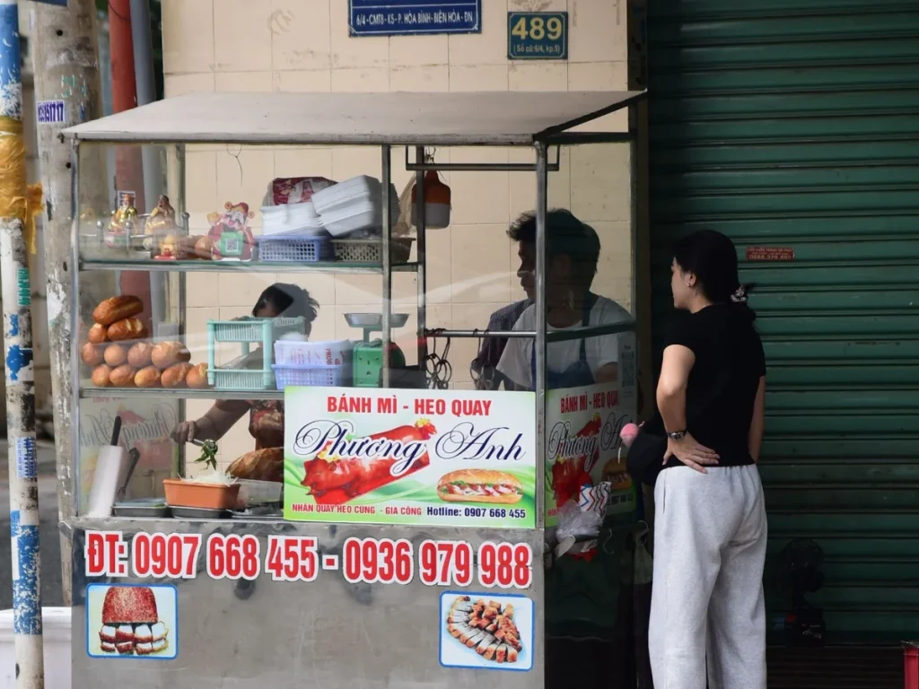 Xe bánh mì ngoài đường với khu vực thao tác và khách đứng nhận hàng
