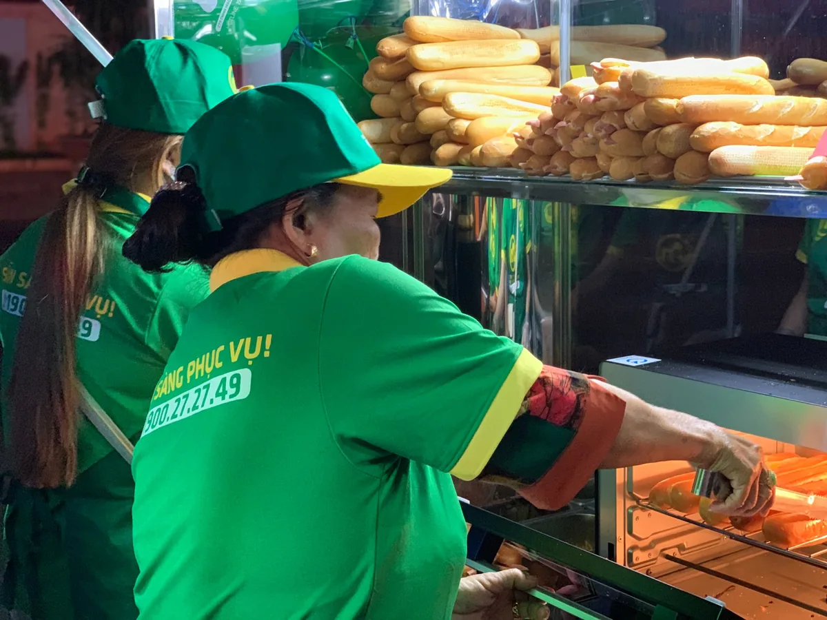Nhân viên tại quầy bánh mì đang chuẩn bị bánh và làm nóng sản phẩm